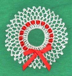 a white doily with a red ribbon around it on a green tablecloth background