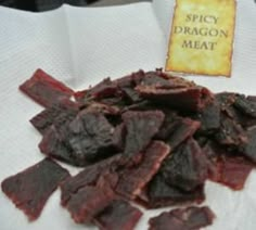 a pile of red meat sitting on top of a white paper towel next to a sign