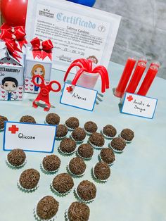 a table topped with lots of cupcakes covered in chocolate frosting and red ribbon