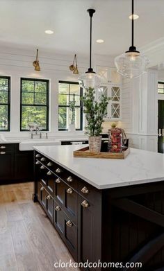 a large kitchen with black cabinets and white counter tops, along with an island in the middle