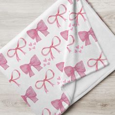 pink bows and hearts on white paper napkins sitting on top of a wooden table