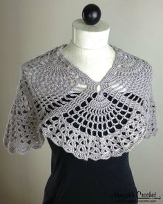 a white crochet top on a mannequin head stand with a black dress underneath it