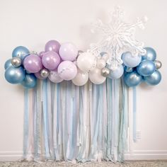 a bunch of balloons that are hanging on a wall next to a curtain with snowflakes