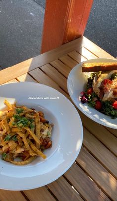 two white plates with food on them sitting on top of a wooden table next to each other