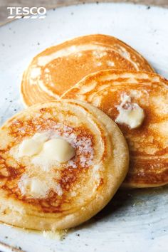 three pancakes on a white plate topped with butter