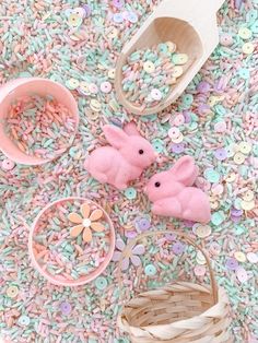 two pink stuffed animals sitting on top of a floor next to bowls and spoons