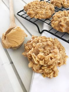 cookies with peanut butter are on cooling racks next to a cookie scooper and some oatmeal