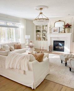 a living room filled with furniture and a fire place under a chandelier in front of a window