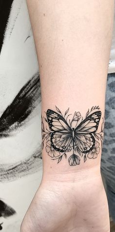 a black and white butterfly tattoo on the wrist