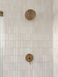 a shower head and hand held shower faucet in a white tiled bathroom stall