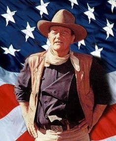 a man wearing a cowboy hat standing in front of an american flag with his hands on his hips