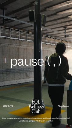 a woman walking down a street next to a pole with a sign on it that says pause