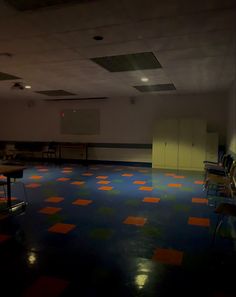 an empty room with several tables and chairs in the center, all lit up by spotlights