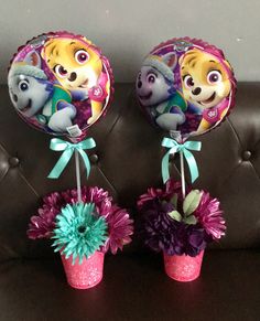 there are two balloons with animals on them and flowers in the vases next to each other