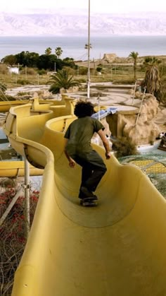 a man riding a skateboard down the side of a water slide at a park