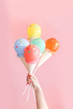 a person holding up balloons in the air with confetti on them and sprinkles