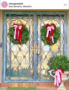 two wreaths with red bows are on the front door