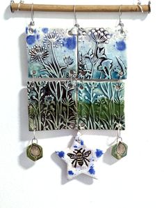 a wall hanging made out of ceramic tiles with flowers and a bee on the side