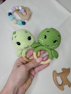 two crocheted octopus rings are held by a person's hand, with other toys nearby