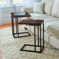 two tables sitting on top of a rug in front of a couch with a laptop