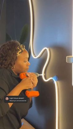 a woman sitting in front of a neon sign with an orange light on it's side