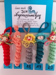 four crocheted dolls are on display in front of a sign that says less much