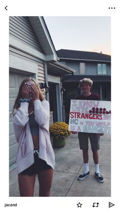 two people standing in front of a house holding signs that read, i know strangers