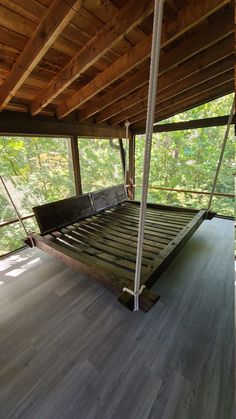 an empty bed frame in the middle of a room with wood flooring and wooden ceiling