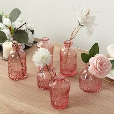 pink glass vases with flowers in them on a table