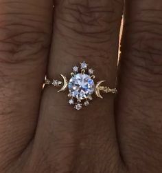 a woman's hand with an engagement ring on it and the moon in the middle