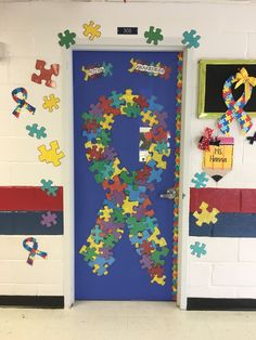 a door decorated with puzzle pieces in the shape of a ribbon and an awareness symbol