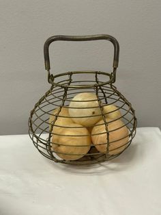 a wire basket filled with potatoes sitting on top of a white tablecloth covered table