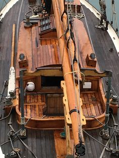 an old wooden sailboat with ropes and steering wheel on the front deck, looking down