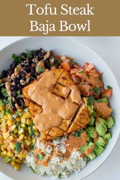 a white bowl filled with rice, beans and tofu steak on top of it