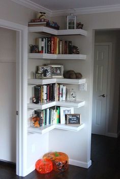 there is a bookshelf in the room with many books on it and two orange pumpkins