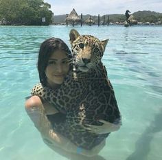 a woman holding a leopard in the water