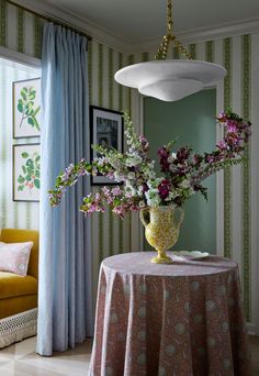 a vase filled with flowers sitting on top of a table next to a yellow chair