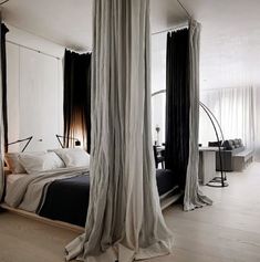 a bedroom with black and white drapes hanging from the ceiling next to a bed