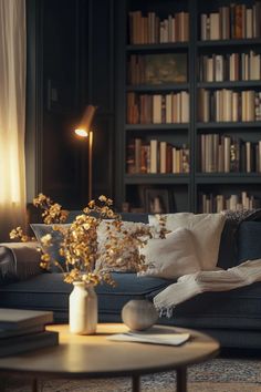 a living room with bookshelves and couches filled with pillows, vases and flowers