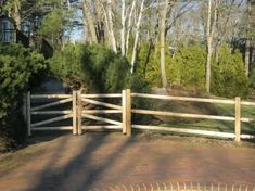 a wooden gate is in the middle of a brick walkway with trees and bushes behind it