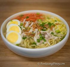 a bowl filled with noodles and eggs on top of a wooden table