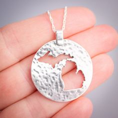 Flaunt your Michigan pride with this lovely sterling silver pendant.  Both peninsulas of Michigan are cut out of a large silver circle that has been textured to catch the light.This pendant measures approximately 1 1/8th inches in diameter, not including the bail.  Each pendant comes with a sterling silver chain at no extra charge. Please specify 16, 18, or 20 inches long for the chain.  If in doubt, 18 inch chains work well for most people. The pendant will come to you gift boxed, whether it is Etched Sterling Silver Round Pendant Jewelry, Hammered Sterling Silver Medallion Jewelry, Sterling Silver Hammered Medallion Jewelry, Etched Sterling Silver Round Disc Jewelry, Sterling Silver Coin Pendant Jewelry, Symbolic Silver Hammered Jewelry, Silver Circle, Sterling Silver Chain, Sterling Silver Pendant