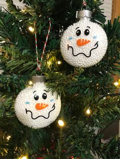 two snowman ornaments hanging from a christmas tree