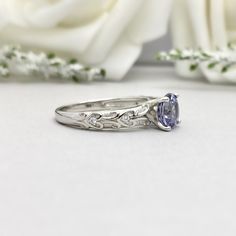 a close up of a ring on a table with flowers in the background and white roses