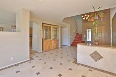 a large foyer with tile floors and stairs leading up to the second floor, next to a staircase