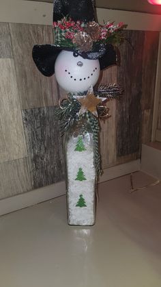 a snowman in a black hat is sitting on the counter next to a wall