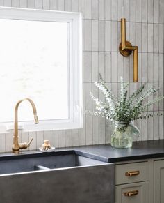 a vase with flowers in it sitting on a kitchen counter next to a sink and window