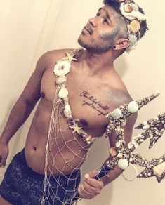 a man with no shirt on holding a starfish and seashells in his hand