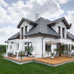 a large white house sitting on top of a lush green field next to a wooden deck