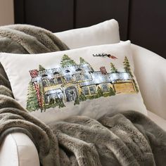 a white chair with a pillow on top of it next to a blanket and pillows